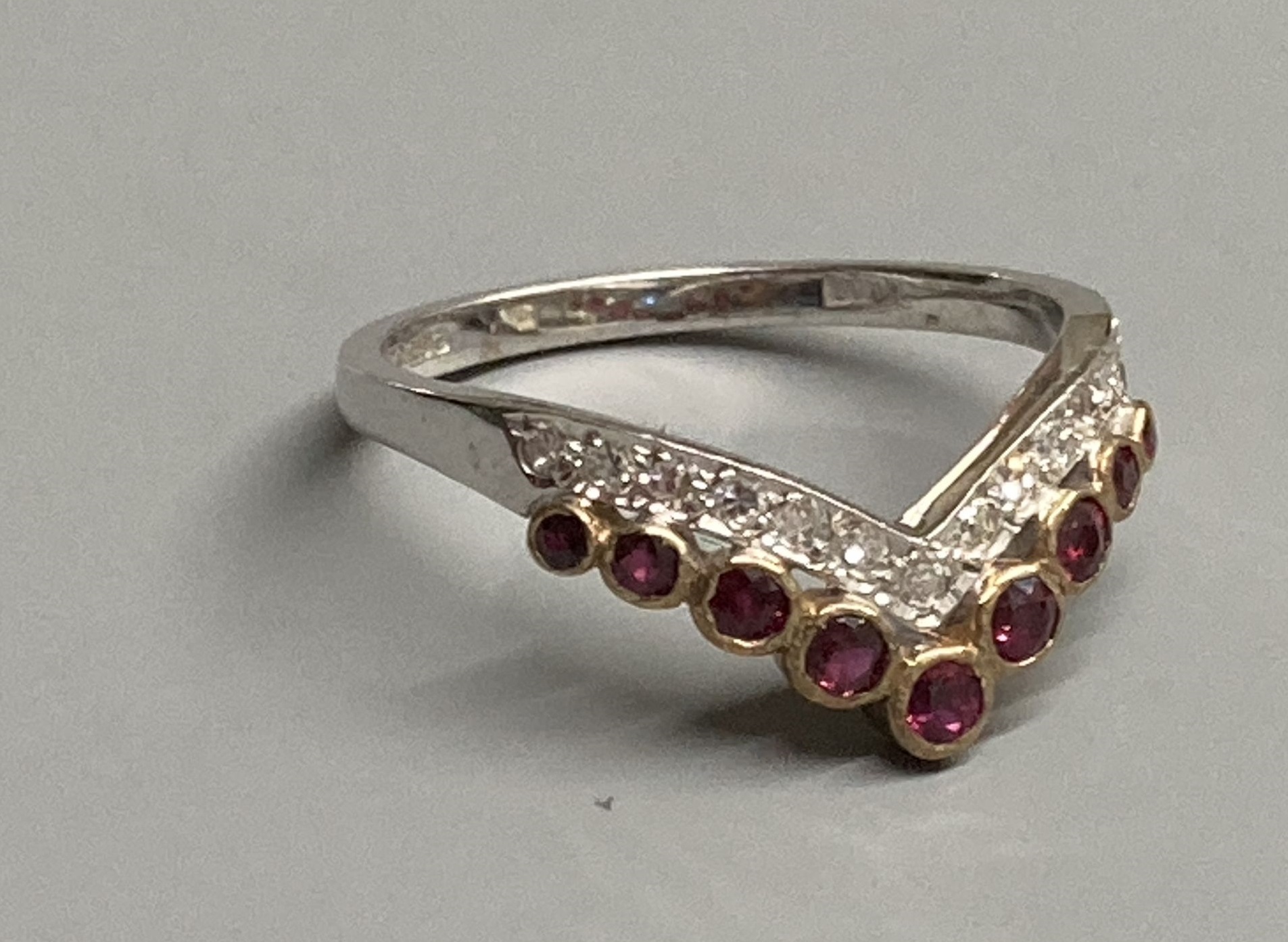 A modern 18ct gold, two row ruby and diamond set chevron ring, size M/N, gross 2.1 grams.